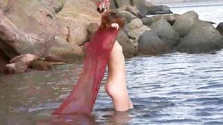 A sexy girl is walking on the naked beach and playing with her boobs