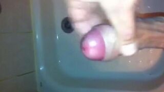 The kid masturbates his cock with his hand in the shower