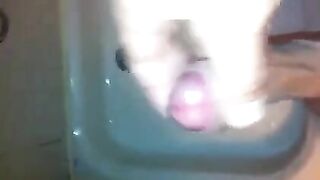The kid masturbates his cock with his hand in the shower