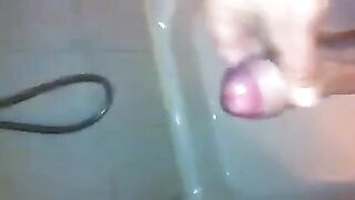 The kid masturbates his cock with his hand in the shower