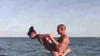 Nude beauties do acrobatic poses on the sandy beach